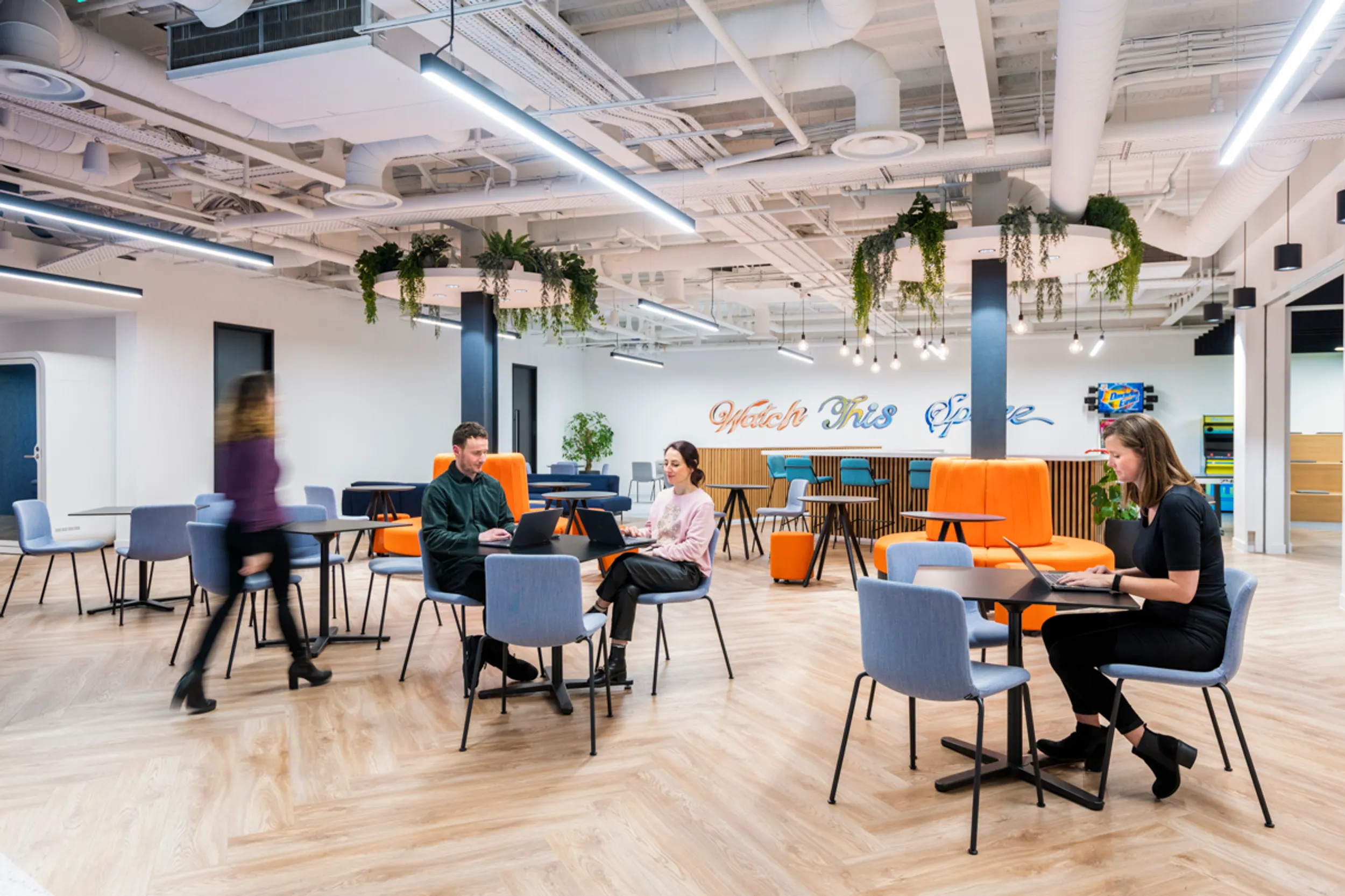 a newly designed hybrid office space with people working at tables