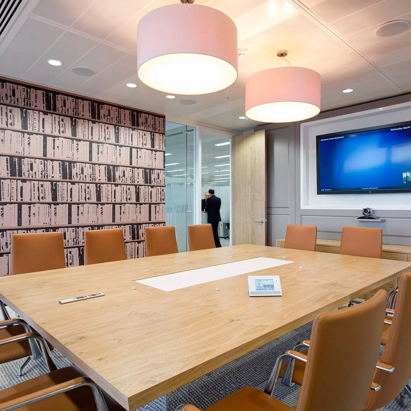 a large meeting room with square wooden table and large tv screen