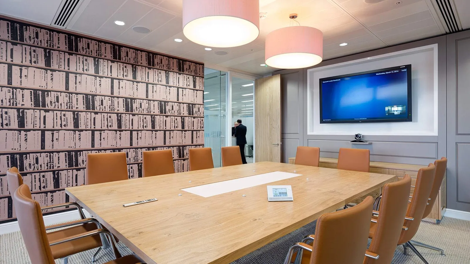 a large meeting room with square wooden table and large tv screen