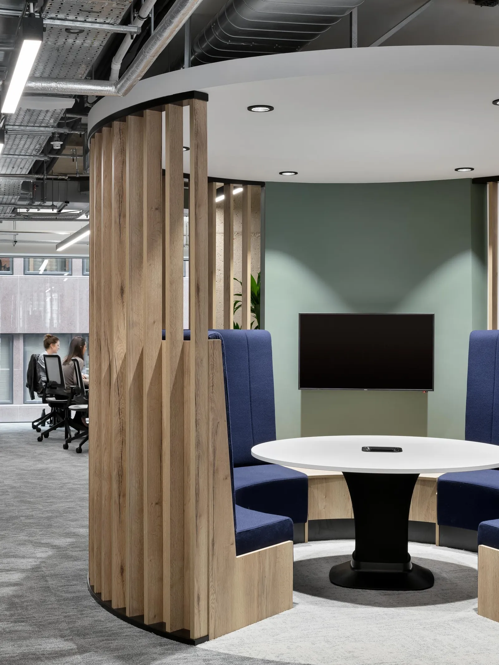 a circular meeting room with tv in open planned office